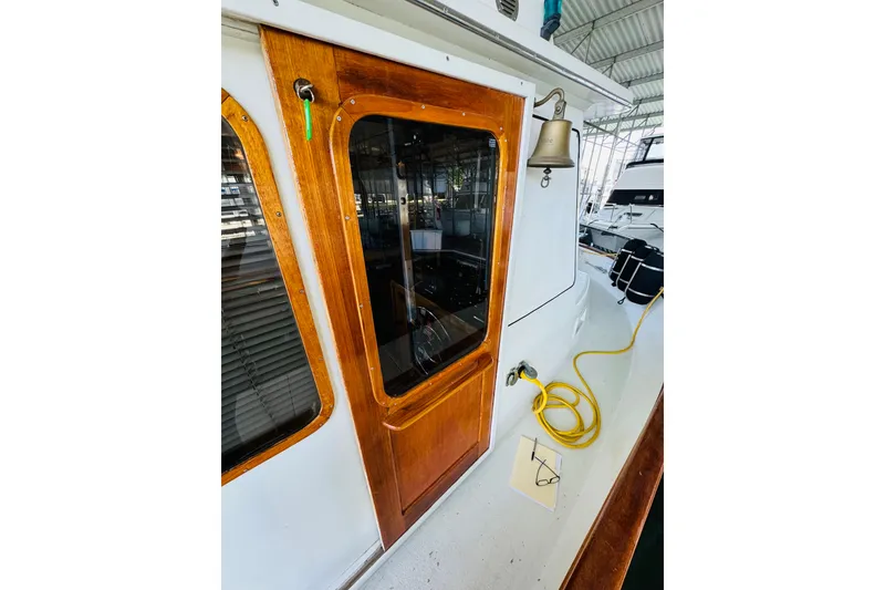 Slide: The Image of 1978 Californian 42 LRC boat with wooden door, bell, and yellow hose on deck. - 19