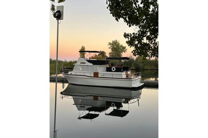 Slide: The Image of 1978 Californian 42 LRC yacht on calm water at sunset, reflecting trees and sky. - 4
