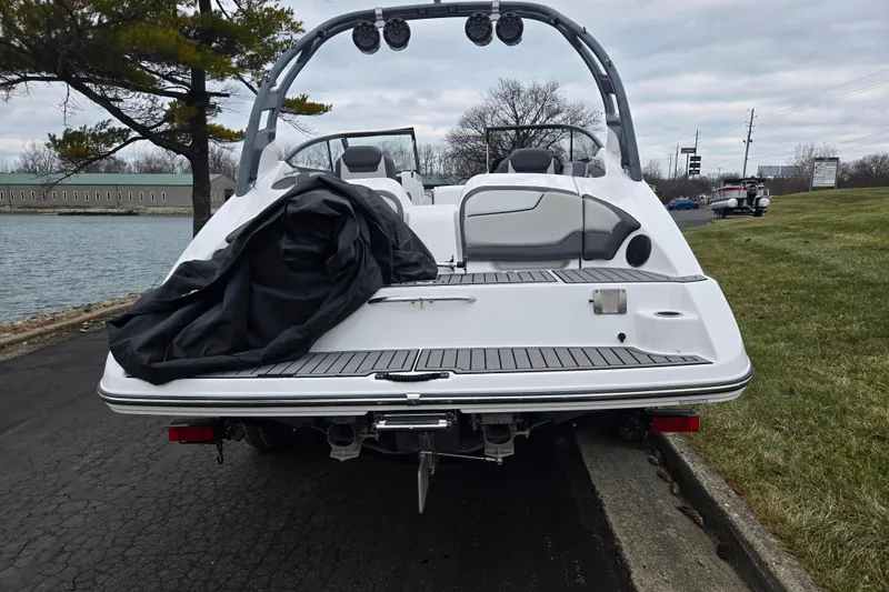 Slide: The Image of 2017 Yamaha Boats 212 Limited S at lakeside, rear view with cover partially removed. - 2