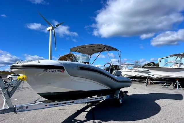 Slide: The Image of 2023 Zodiac N-ZO 680 boat on trailer, parked outdoors under blue sky with wind turbine. - 8