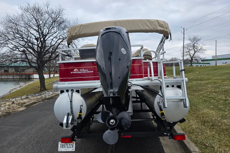 Slide: The Image of 2020 Sun Tracker Bass Buggy 18 DLX pontoon boat on trailer by a lake. - 2