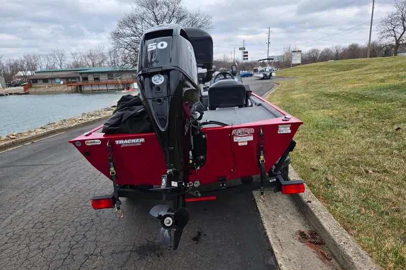 Slide: The Image of 2024 Tracker Bass Tracker Classic XL boat with outboard motor, parked near a lake. - 2