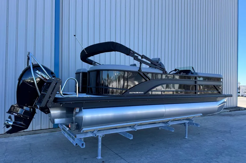 Slide: The Image of 2026 Bennington 22 SSR pontoon boat with Mercury outboard, parked by a metal building. - 3