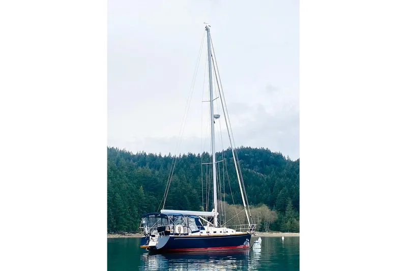 Slide: The Image of Sailboat Tartan 395, 2019 model, anchored in serene forested bay. - 2