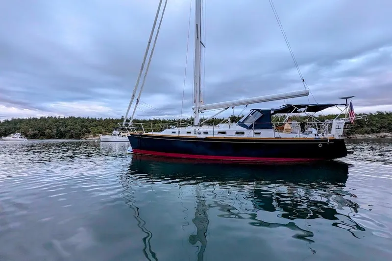 Slide: The Image of Sailboat on calm water, Tartan 395, 2019 model, with scenic forest backdrop. - 4