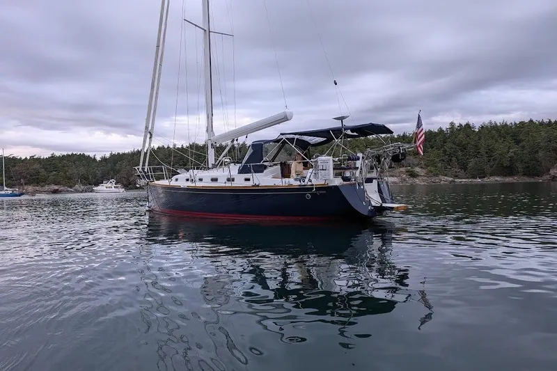 Slide: The Image of Sailboat Tartan 395, 2019 model, anchored in a scenic bay with forested shoreline. - 5
