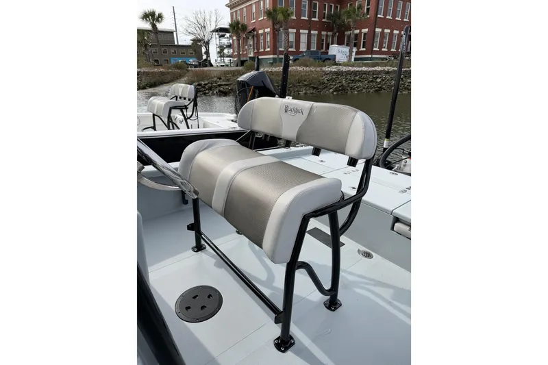 Slide: The Image of 2023 BlackJack 256 Bay boat with cushioned seating, docked near a brick building. - 10
