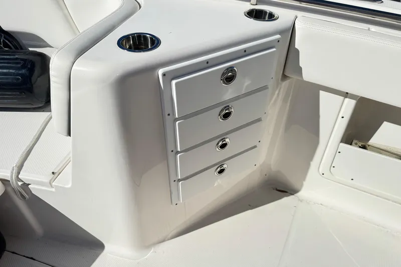 Slide: The Image of 2023 Robalo R302 Center Console boat interior with storage drawers and cup holders. - 8