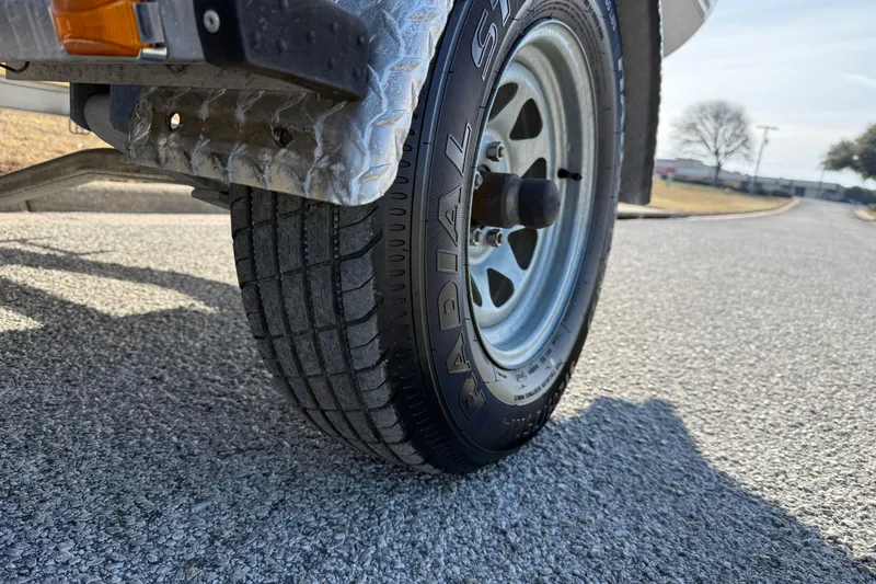 Slide: The Image of Close-up of a 2023 Sun Tracker Party Barge 18 DLX trailer tire on a sunny road. - 24
