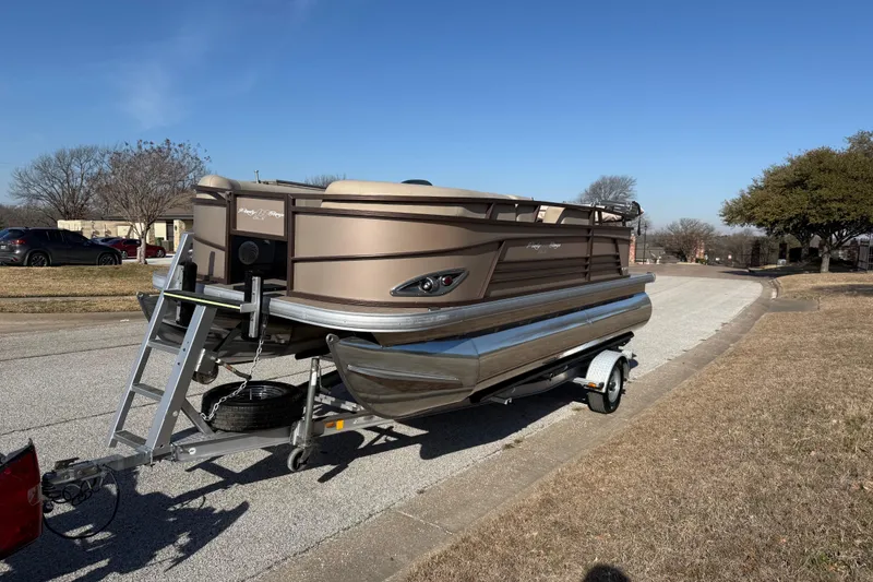 Slide: The Image of 2023 Sun Tracker Party Barge 18 DLX pontoon boat on trailer, parked on suburban street. - 26