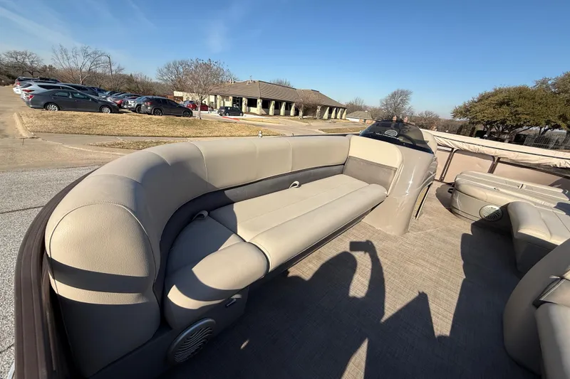 Slide: The Image of 2023 Sun Tracker Party Barge 18 DLX interior with beige seating, parked outdoors. - 31
