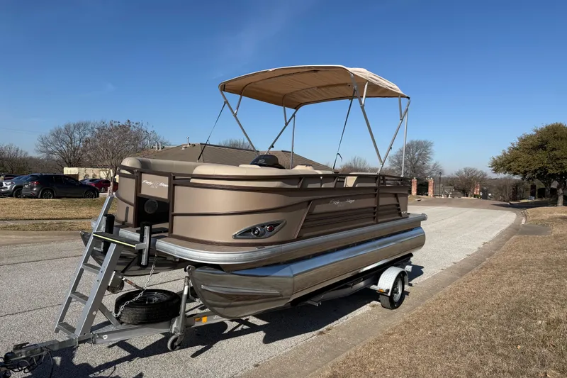 Slide: The Image of 2023 Sun Tracker Party Barge 18 DLX pontoon boat on trailer, parked on suburban street. - 53