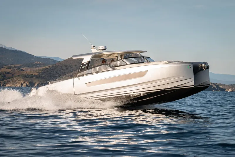 Slide: The Image of 2025 YOT 36 motor yacht cruising on open water near scenic coastline. - 2