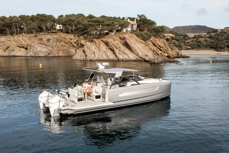 Slide: The Image of 2025 YOT 36 boat anchored near rocky coastline with people relaxing onboard. - 8