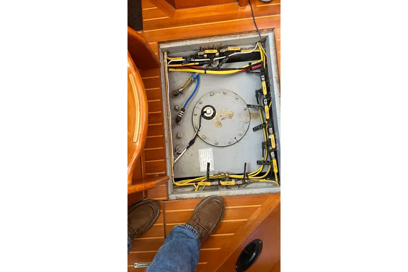Slide: The Image of Electrical panel inside 2006 Tayana Cutter sailboat, featuring wiring and connections on wooden flooring. - 11