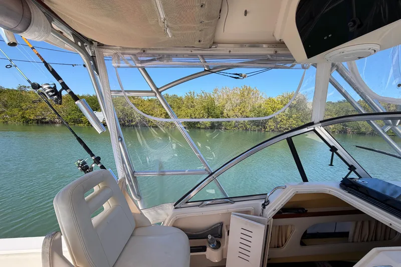 Slide: The Image of 2006 Grady-White Sailfish 282 interior with fishing rods, calm water, and lush greenery. - 109