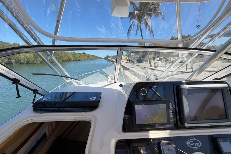 Slide: The Image of 2006 Grady-White Sailfish 282 boat cockpit with navigation screens, docked by a scenic waterway. - 112