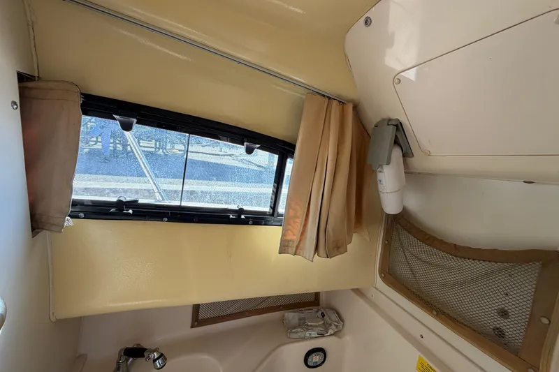 Slide: The Image of 2006 Grady-White Sailfish 282 cabin interior with window, curtains, and storage net. - 143