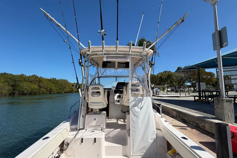 Slide: The Image of 2006 Grady-White Sailfish 282 boat docked, equipped with fishing rods, under clear blue sky. - 76