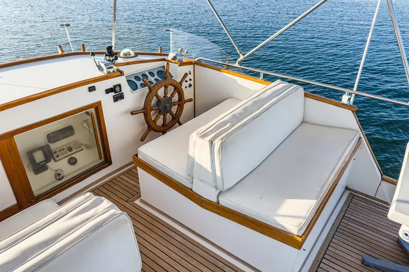 Slide: The Image of 1984 Grand Banks 42 Classic yacht helm with wooden wheel and cushioned seating. - 11