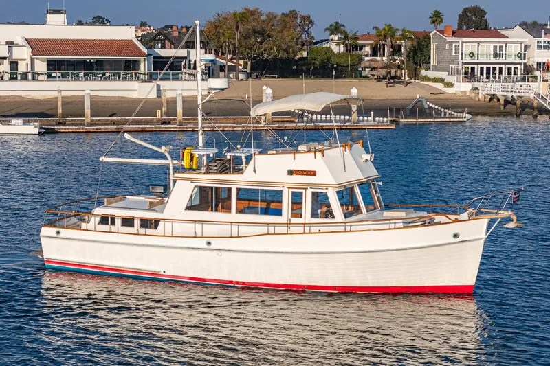 Slide: The Image of 1984 Grand Banks 42 Classic yacht cruising near a coastal marina. - 2