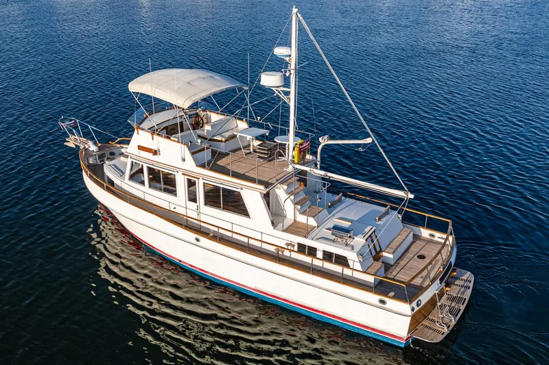 Slide: The Image of 1984 Grand Banks 42 Classic yacht on calm water, showcasing elegant design and spacious deck. - 3