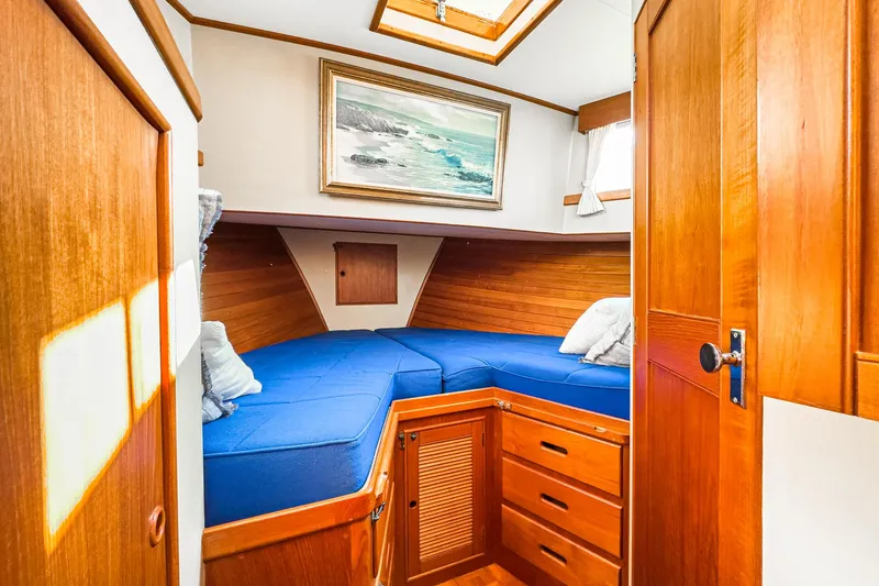 Slide: The Image of 1984 Grand Banks 42 Classic cabin with blue bedding, wooden interior, and nautical decor. - 42