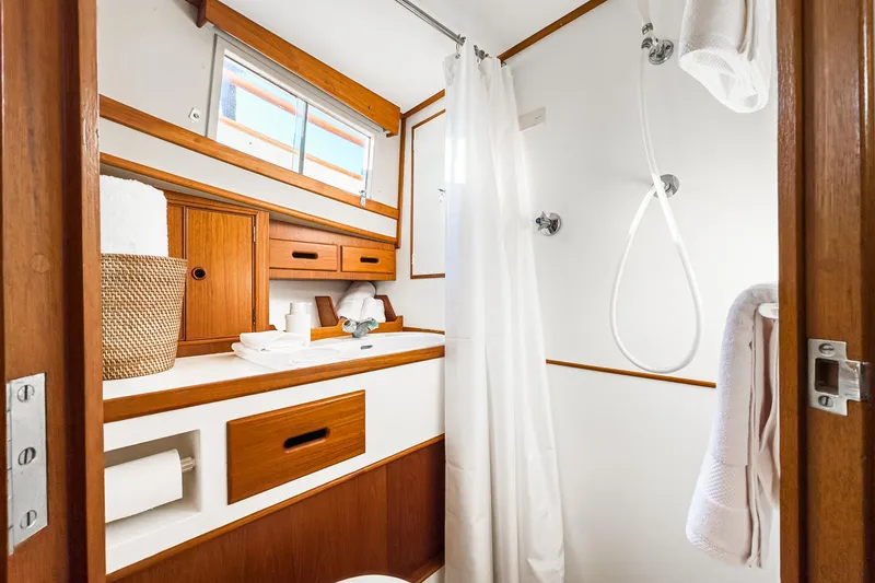 Slide: The Image of 1984 Grand Banks 42 Classic yacht bathroom with wooden cabinetry, shower, and window. - 46