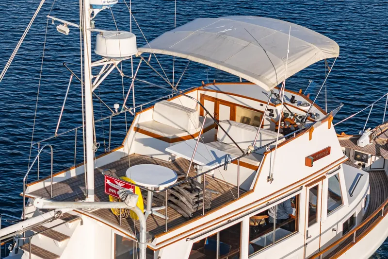 Slide: The Image of 1984 Grand Banks 42 Classic yacht with canopy, cruising on calm blue waters. - 8