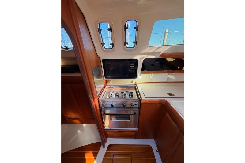 Slide: The Image of 1996 Hunter 336 yacht interior kitchen with stove, microwave, and wooden cabinetry. - 32