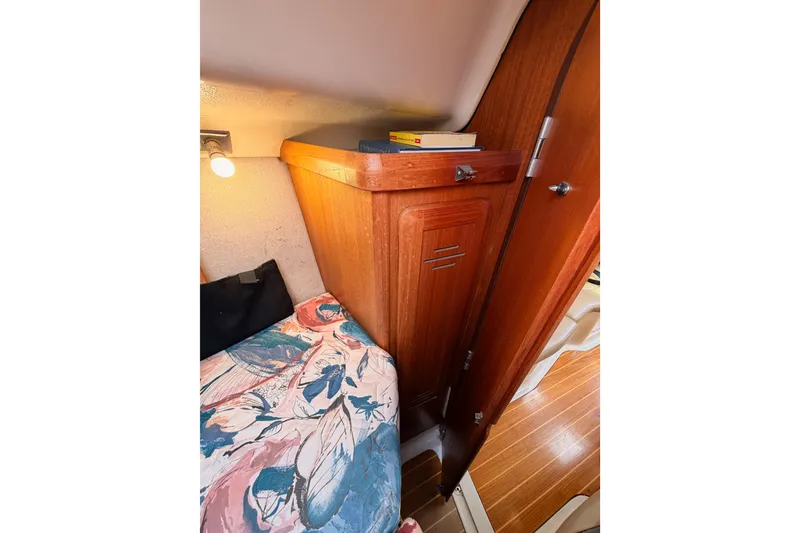 Slide: The Image of Interior of a 1996 Hunter 336 sailboat with wooden cabinetry and floral bedding. - 52