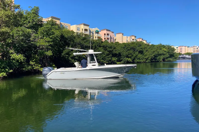 Slide: The Image of 2023 Sea Hunt Gamefish 27 boat cruising on a calm waterway with lush greenery. - 31