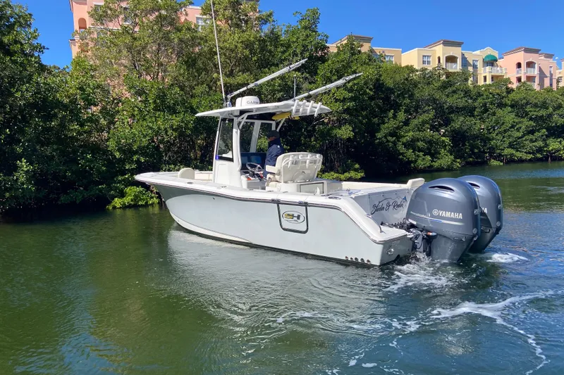 Slide: The Image of 2023 Sea Hunt Gamefish 27 boat cruising on a scenic waterway with lush greenery. - 5