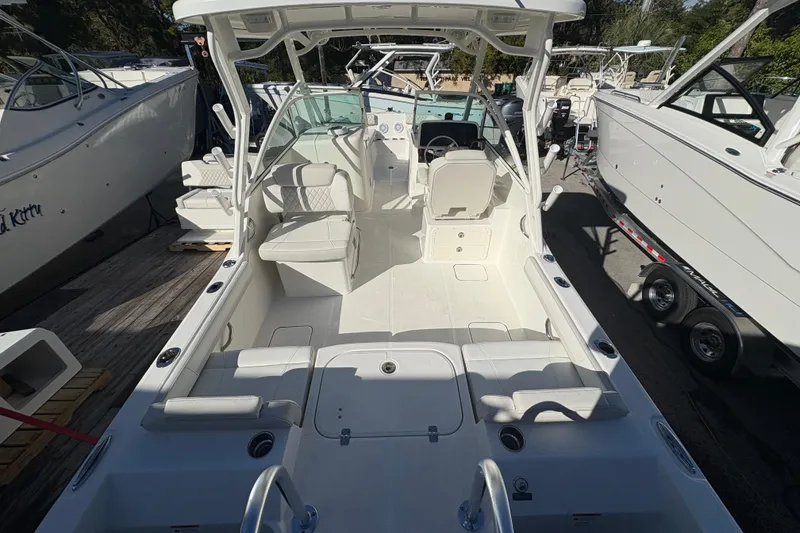 Slide: The Image of 2025 World Cat 230 DC boat interior with seating and helm, docked among other boats. - 3