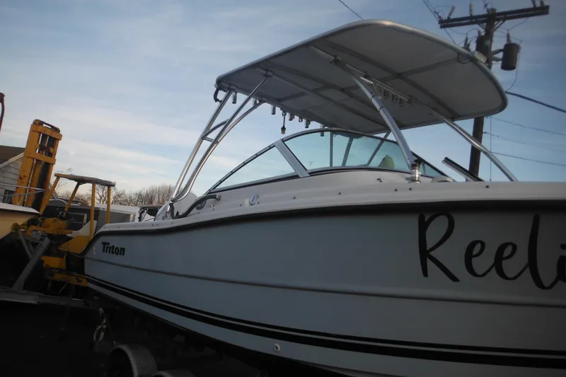 Slide: The Image of 2006 Triton 225 DC boat with canopy, parked near utility poles. - 11