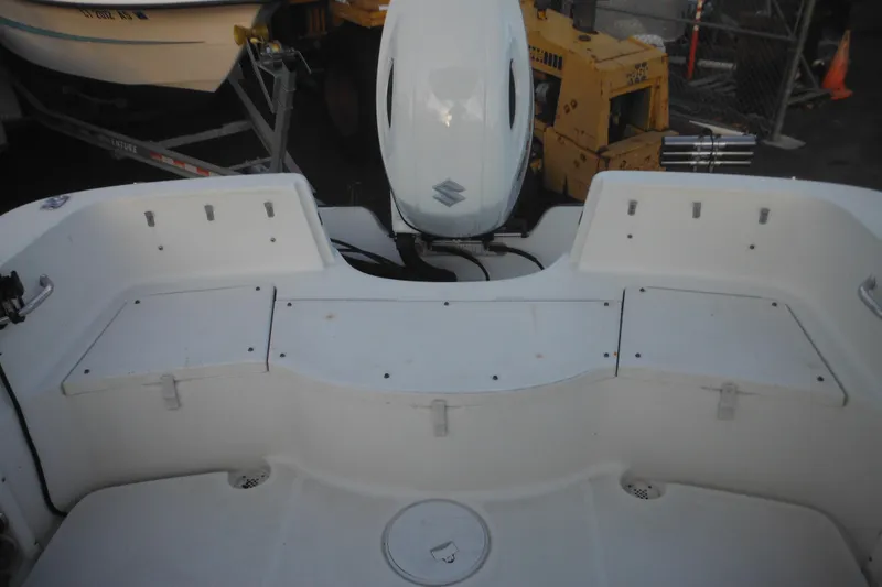 Slide: The Image of 2006 Triton 225 DC boat interior with Suzuki outboard motor, docked in a marina. - 15