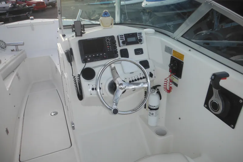 Slide: The Image of 2006 Triton 225 DC boat cockpit with steering wheel, controls, and navigation equipment. - 23