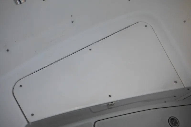 Slide: The Image of 2006 Triton 225 DC boat storage compartment with white cover and screws. - 26