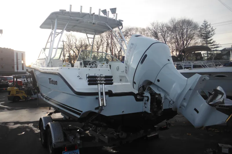 Slide: The Image of 2006 Triton 225 DC boat on trailer with outboard motor, parked outdoors. - 3
