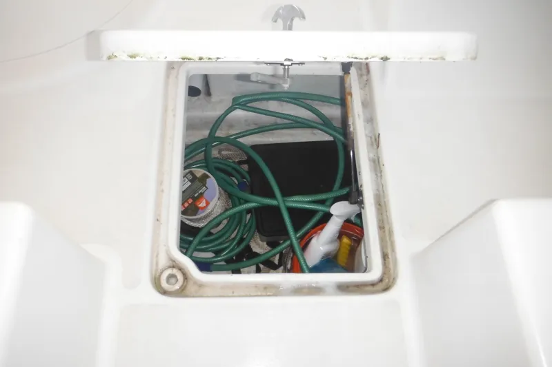 Slide: The Image of Open storage compartment on 2006 Triton 225 DC boat with hose and cleaning supplies. - 45
