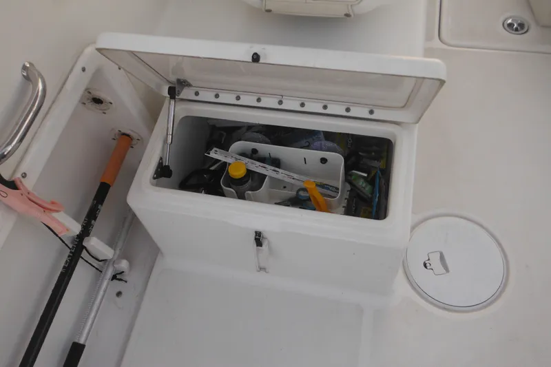Slide: The Image of Open storage compartment on 2006 Triton 225 DC boat, containing various tools and equipment. - 51
