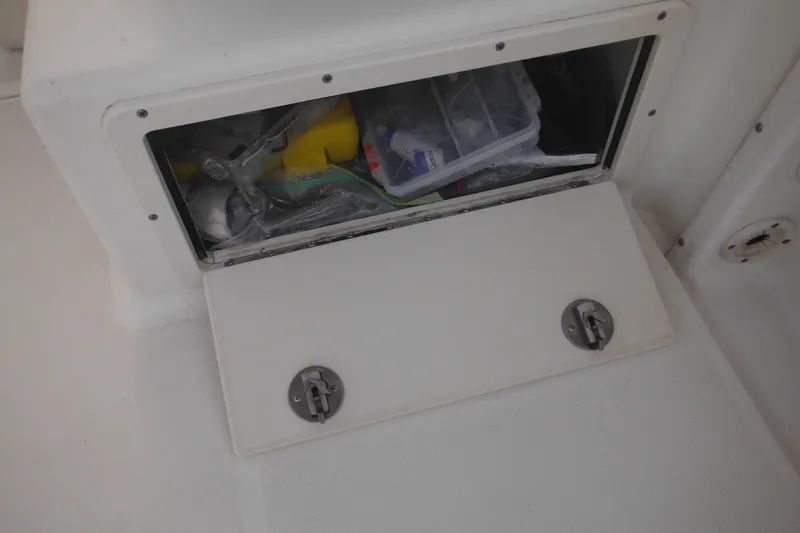 Slide: The Image of Storage compartment on a 2006 Triton 225 DC boat, containing various items. - 52