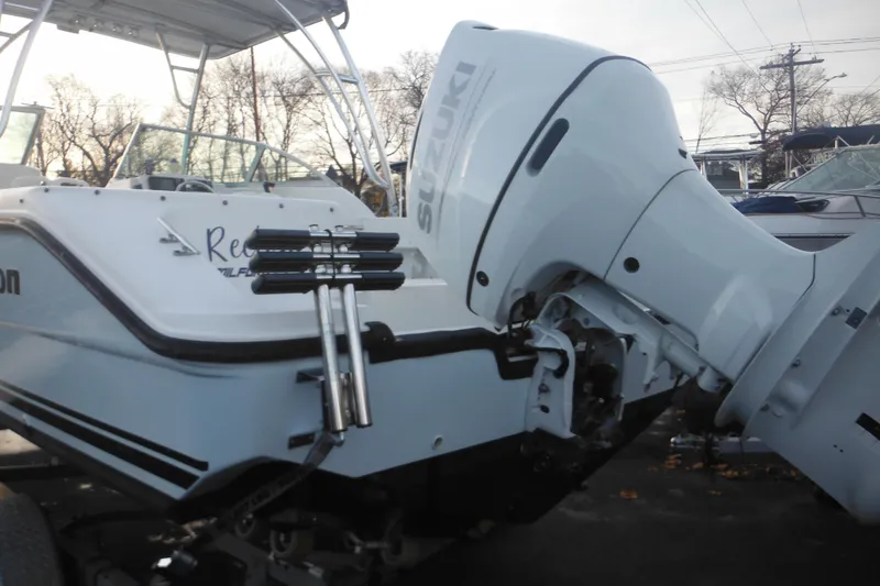 Slide: The Image of 2006 Triton 225 DC boat with Suzuki outboard motor, parked on a trailer. - 8