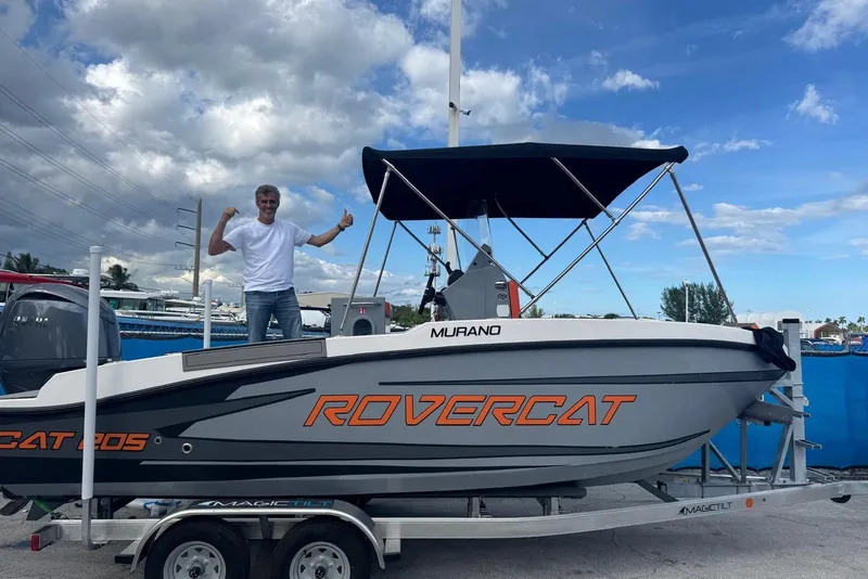 Slide: The Image of 2026 Murano Yachts Rovercat 205 on trailer, man celebrating beside it. - 1