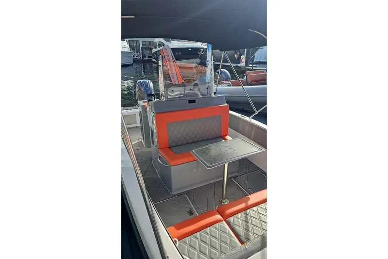 Slide: The Image of 2026 Murano Yachts Rovercat 205 interior with orange seating and table, docked at marina. - 8