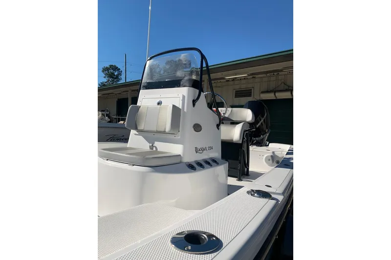 Slide: The Image of 2018 BlackJack 224 boat with console and seating, docked outdoors. - 12