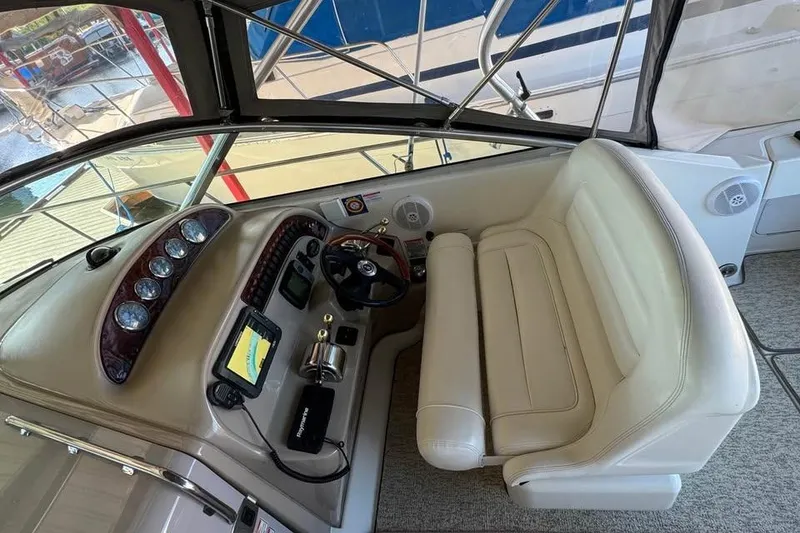Slide: The Image of 2003 Sea Ray 290 Amberjack helm with gauges, steering wheel, and beige seating. - 11