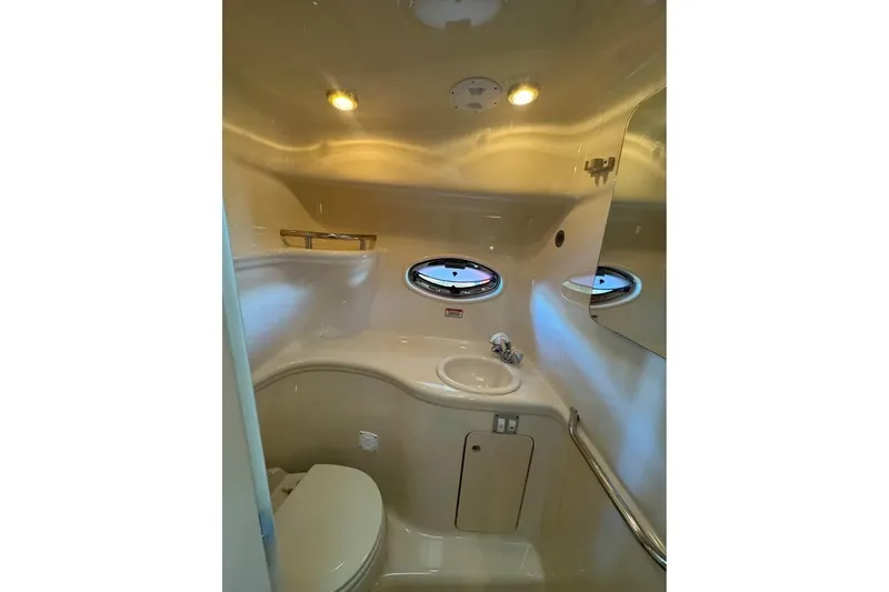 Slide: The Image of 2003 Sea Ray 290 Amberjack bathroom interior with sink, toilet, and porthole window. - 14