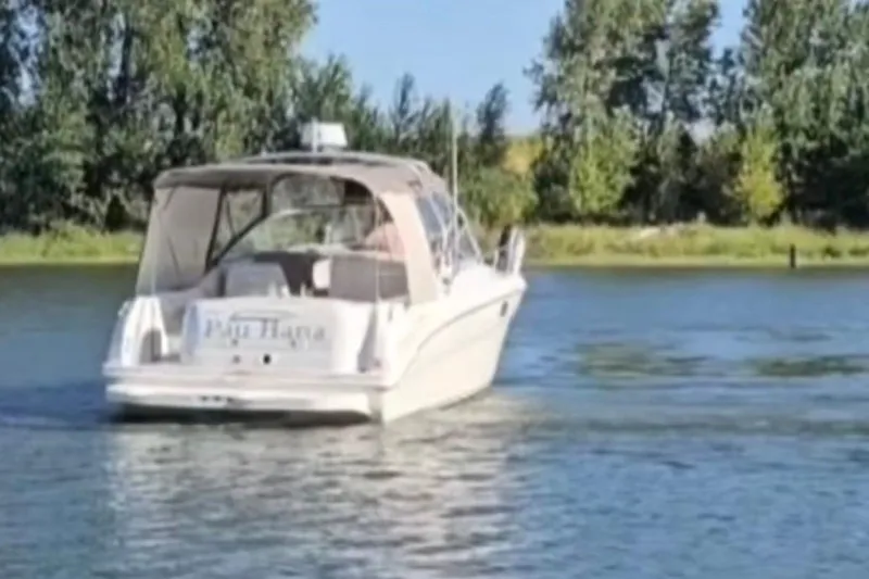 Slide: The Image of 2003 Sea Ray 290 Amberjack boat on a calm river with trees in the background. - 21