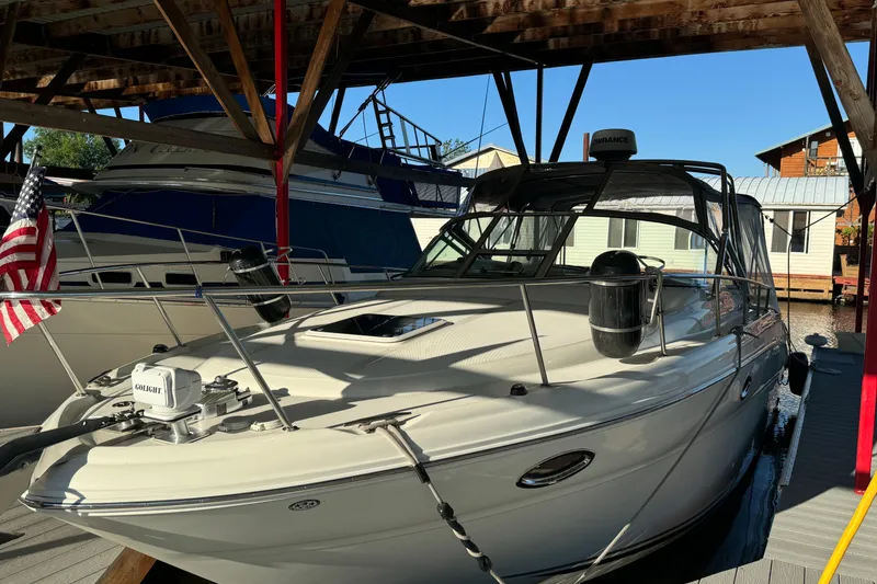 Slide: The Image of 2003 Sea Ray 290 Amberjack docked under a wooden shelter with American flag. - 5